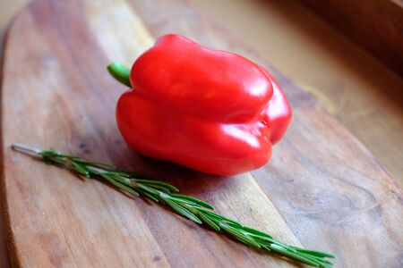Fresh rosemary and sweet red bell pepper on a wooden background. The concept of a delicious and healthy diet.の写真素材