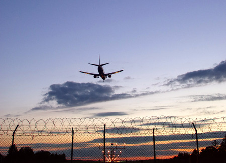 Skyline of passangers airplane landing at sunsetの写真素材