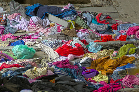 Abandoned heap of old worn clothes. Scattered colorful fabric.