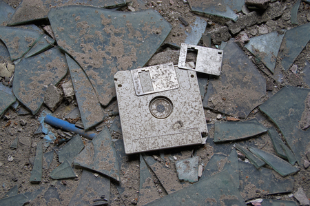 Destroyed and abandoned vintage floppy disc. Forgotten technologies - 3.5 inch disk in plastic case on broken glass.の写真素材