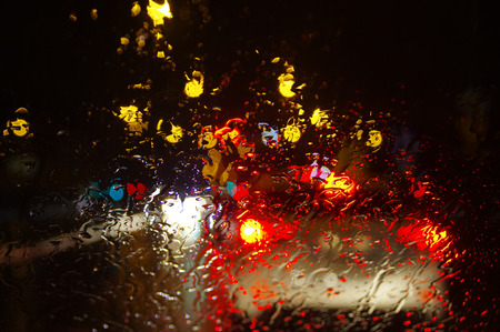 Raindrops on car window. City lights blurred by water drops on glass.