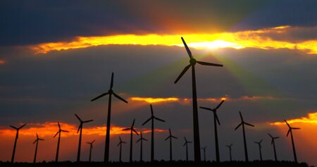 Wind turbines silhouette on dramatic sky background. Energy windmills in concept of ecological...