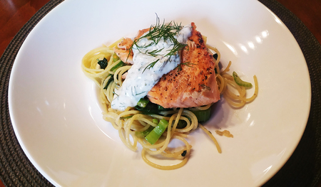 Fresh baked salmon on pasta with spinach and celery. Fish dish served on a deep plate. Healthy eating.の写真素材