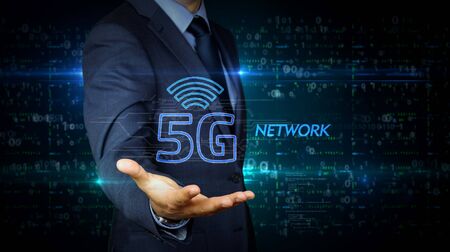 A businessman in a suit and the screen with 5G hologram. Man using hand on virtual display interface. Wireless network, mobile communication, data transmition, internet of things futuristic concept.の写真素材
