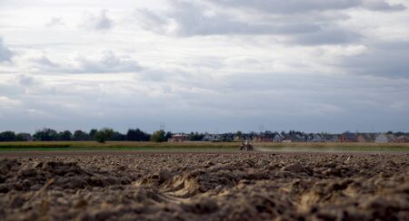 Farmer plowing the dry land with an old tractor in background. Agricultural, drought, soil tillage,...
