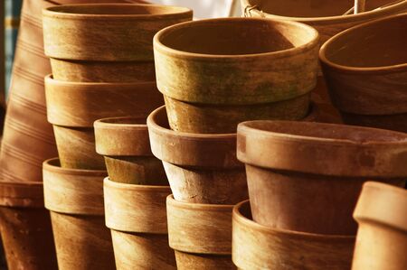 Orange clay pots in the sun. Preparation for spring home gardening. Organic plant cultivation.
