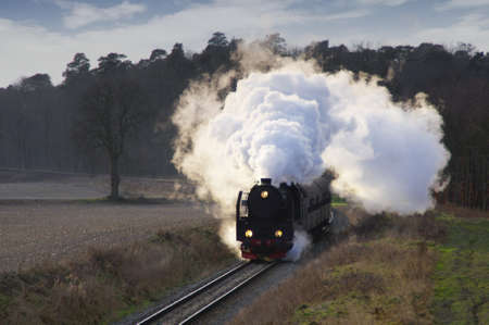 Retro smoky steam locomotive. Old passenger train on the former railway line.の写真素材