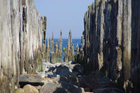 Old wooden breakwater by the sea. Rusty coastal protection.の写真素材