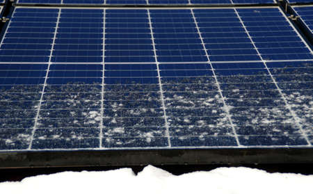 Solar panels covered by snow. Photovoltaic electricity installation on the house roof during winter...