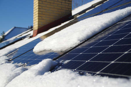 Solar panels covered by snow. Photovoltaic electricity installation on the house roof during winter...