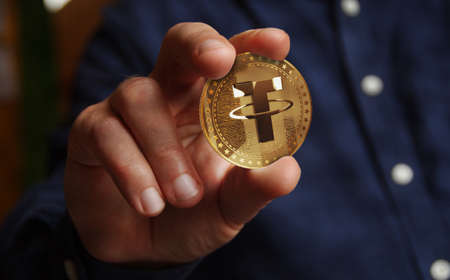 Tether USDT stablecoin cryptocurrency golden coin in hand abstract conceptの写真素材