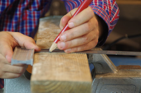 Carpenter in the workshop prepares a cutting raw board. Joiner worker in carpentry shop. A thorough expert and careful craftsman focused on work.の写真素材