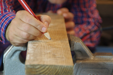 Carpenter in the workshop prepares a cutting raw board. Joiner worker in carpentry shop. A thorough expert and careful craftsman focused on work.の写真素材