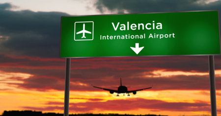 Airplane silhouette landing in Valencia, Spain. City arrival with airport direction signboard and sunset in background. Trip and transportation concept 3d illustration.の写真素材