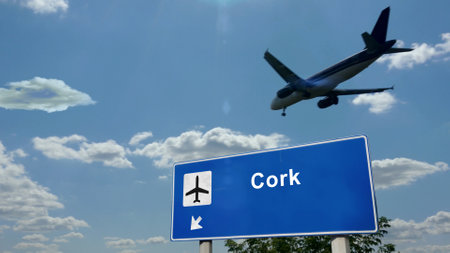 Airplane silhouette landing in Cork, Ireland. City arrival with international airport direction signboard and blue sky. Travel, trip and transport concept 3d illustration.の写真素材