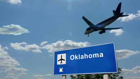 Airplane silhouette landing in Oklahoma, USA. City arrival with international airport direction signboard and blue sky. Travel, trip and transport concept 3d illustration.の写真素材