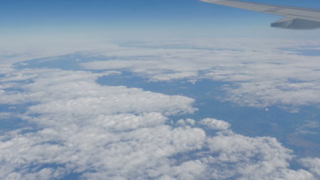 Beautiful view of the blue sky with clouds from the porthole of the plane during the flightの写真素材