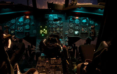 The cockpit of a Chinook helicopter at night with lights glowing