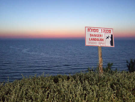 Cliff danger sign over the water, written in Hebrew, English, and Russianの写真素材