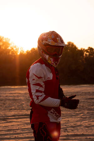 A motorcyclist at sunset looks into the cameraの写真素材