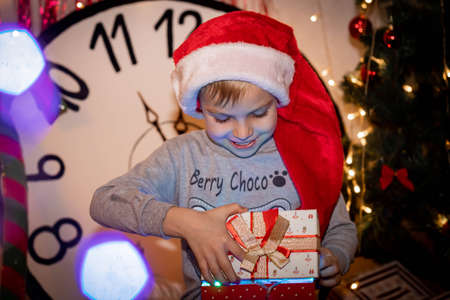 a child in a santa hat opens a giftの写真素材