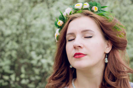 Girl with closed eyes on the background of flowersの写真素材