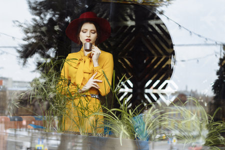 girl in a cafe with a cup of coffee and a hat. beautiful girl with a cup of coffee near the window...