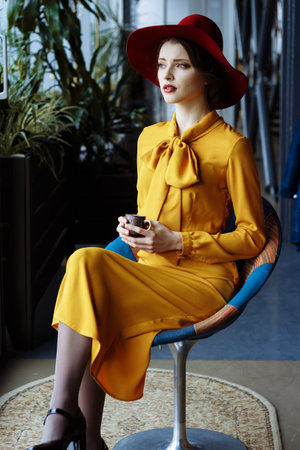 girl in a cafe with a cup of coffee and a hat. beautiful girl with a cup of coffee near the window...