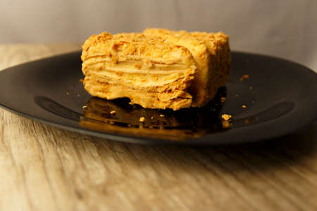 Slice of orange cake on black plate on the wooden table, food background. Napoleonの写真素材