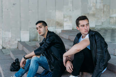 beautiful and attractive guy the city, posing. dressed in a black leather, white T-shirt, jeans and white shoes. walk around the city in black glasses. communication. meeting friends.の写真素材