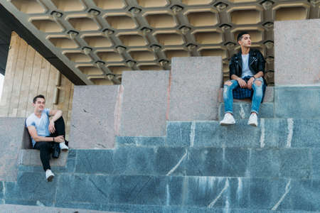 beautiful and attractive guy the city, posing. dressed in a black leather, white T-shirt, jeans and white shoes. walk around the city in black glasses. communication. meeting friends.の写真素材