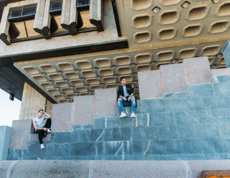 beautiful and attractive guy the city, posing. dressed in a black leather, white T-shirt, jeans and white shoes. walk around the city in black glasses. communication. meeting friends.の写真素材