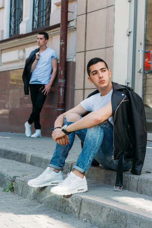 beautiful and attractive guy is standing in the city, posing. walk around the city in black glasses....