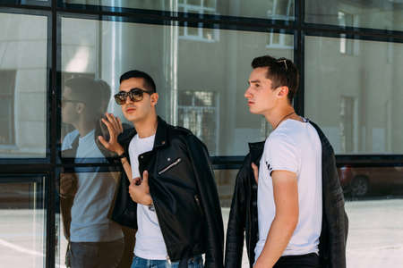 beautiful and attractive guy is standing in the city, posing. walk around the city in black glasses. communication. meeting friends.の写真素材