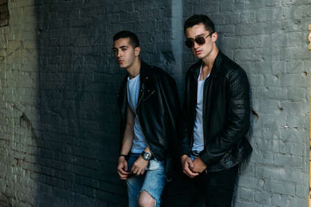 beautiful and attractive guy is standing in the city, posing. near the mirror building. walk around the city in black glasses. communication. meeting friends.の写真素材