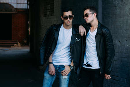 beautiful and attractive guy is standing in the city, posing. near the mirror building. walk around the city in black glasses. communication. meeting friends.の写真素材