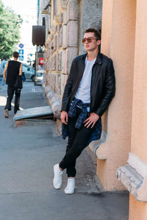 Attractive, sexy guy standing on the street in sunglasses. self-confidence, flatulence and arrogance.model, posing, portrait of a young manの写真素材