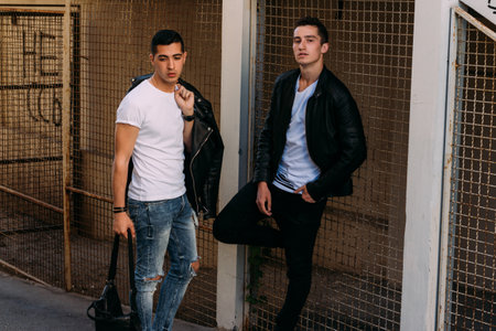 beautiful and attractive guy is standing in the city, posing. dressed in a black leather kurta, white T-shirt, jeans and white shoes.の写真素材