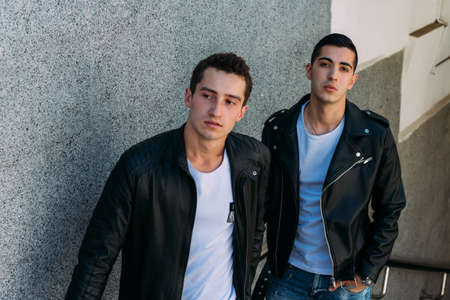 expectation Sexy mans posing near railing. an attractive young mans In a black leather jackets, a white T-shirts and white sneakers is standing near the railing. friendship. two models. showing clothesの写真素材