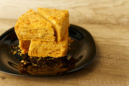 pieces of a layered pie with cream lie on a black plate on the tableの写真素材