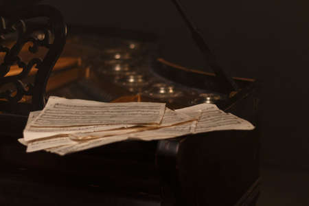 Old sheets with notes lie on a black pianoの写真素材