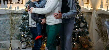 the family of their four people hugging against the background of the Christmas tree. parents and two children. Family photo, photo for memory, New Year's holidays and Christmas in the family.の写真素材