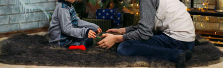 Kids opening Xmas presents. Children under Christmas tree with gift boxes. Decorated living room...