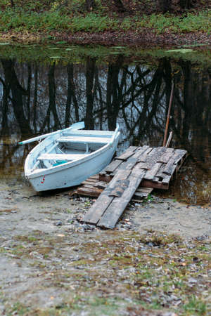 self-made, wooden pier from the old boards on the lake, near are the boats, the river in the mud, duckweedの写真素材