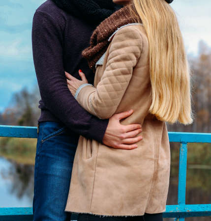 couple embracing on the bridge, near the water, autumn. love and family, a date in the park by the riverの写真素材