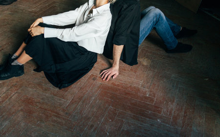 the couple is sitting on the wooden floor, back to back. deployed in different directions. outlook on lifeの写真素材