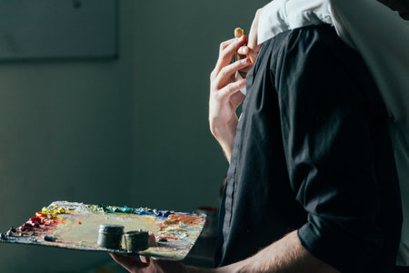 a man holds in his hand a palette with paints and a brush, and behind him they embrace. supportの写真素材