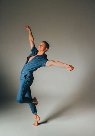 guy dances on a white background in jeans, hands are raised up, jump, pose, styleの写真素材