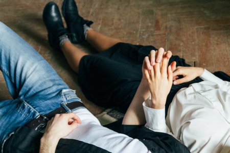 Holding hands. Lovers couple holding hands in a room. Hand in hand.lying on the floorの写真素材