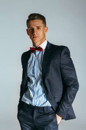 young, attractive guy in suit with butterfly standing in poses on white background, portrait, studio photo, businessman, successの写真素材